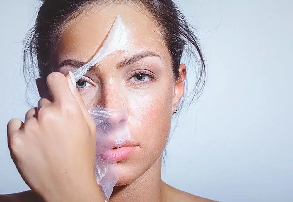 Femme qui retire un film de peeling de son visage