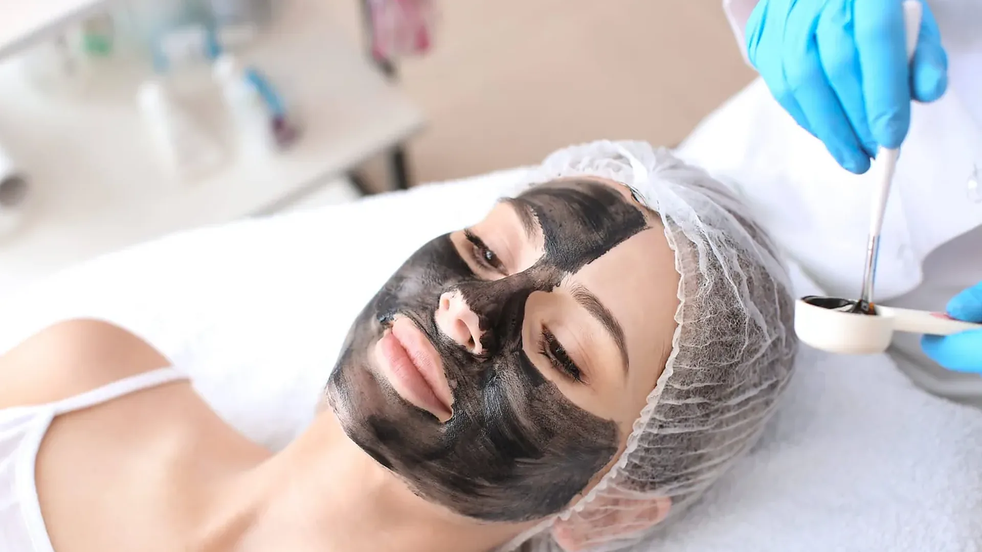 Femme allongée avec un masque au carbone noir sur le visage pendant un carbon peel au laser