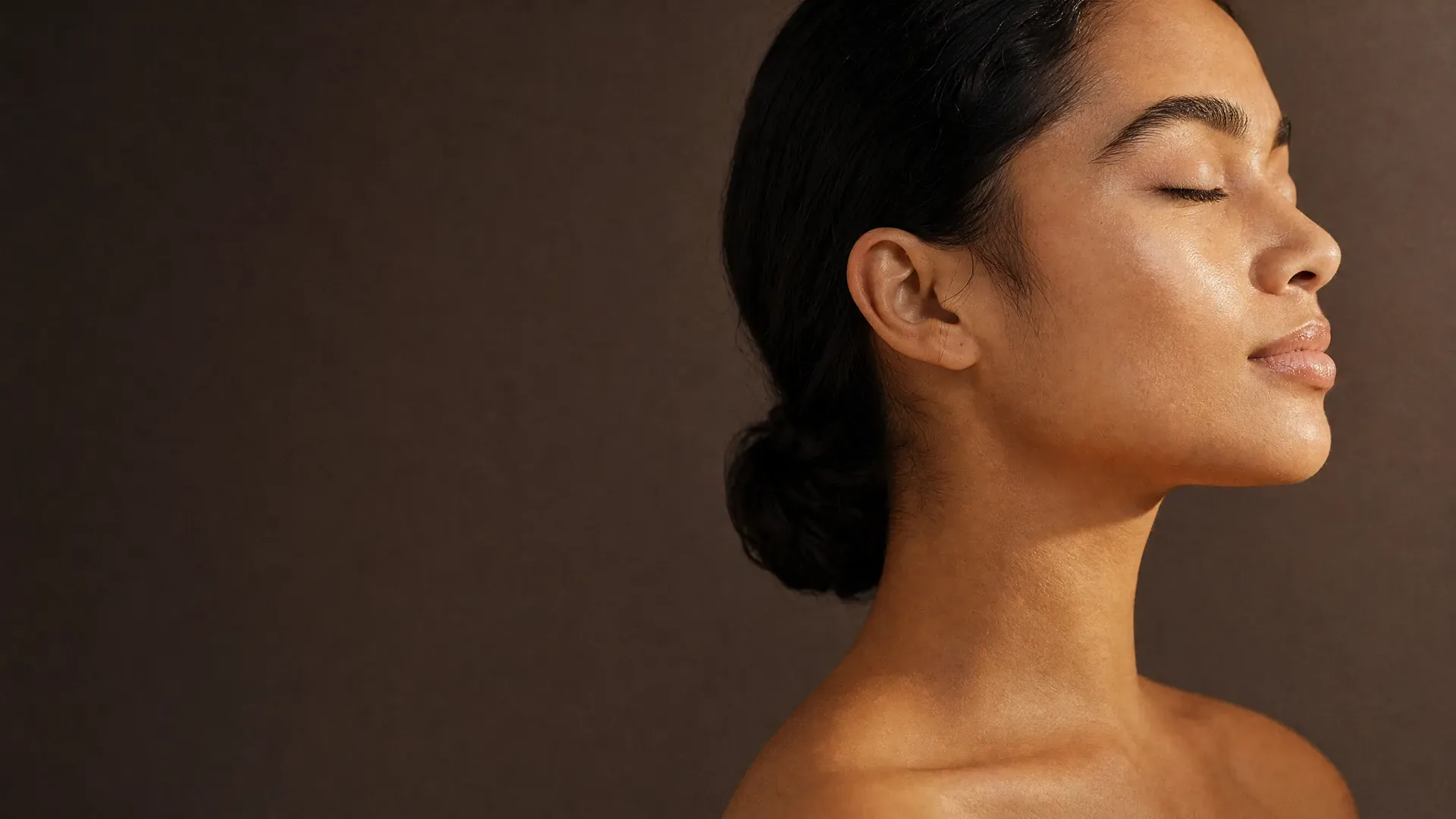 Femme de profil, épaules et cou à la peau nette, sur fond neutre