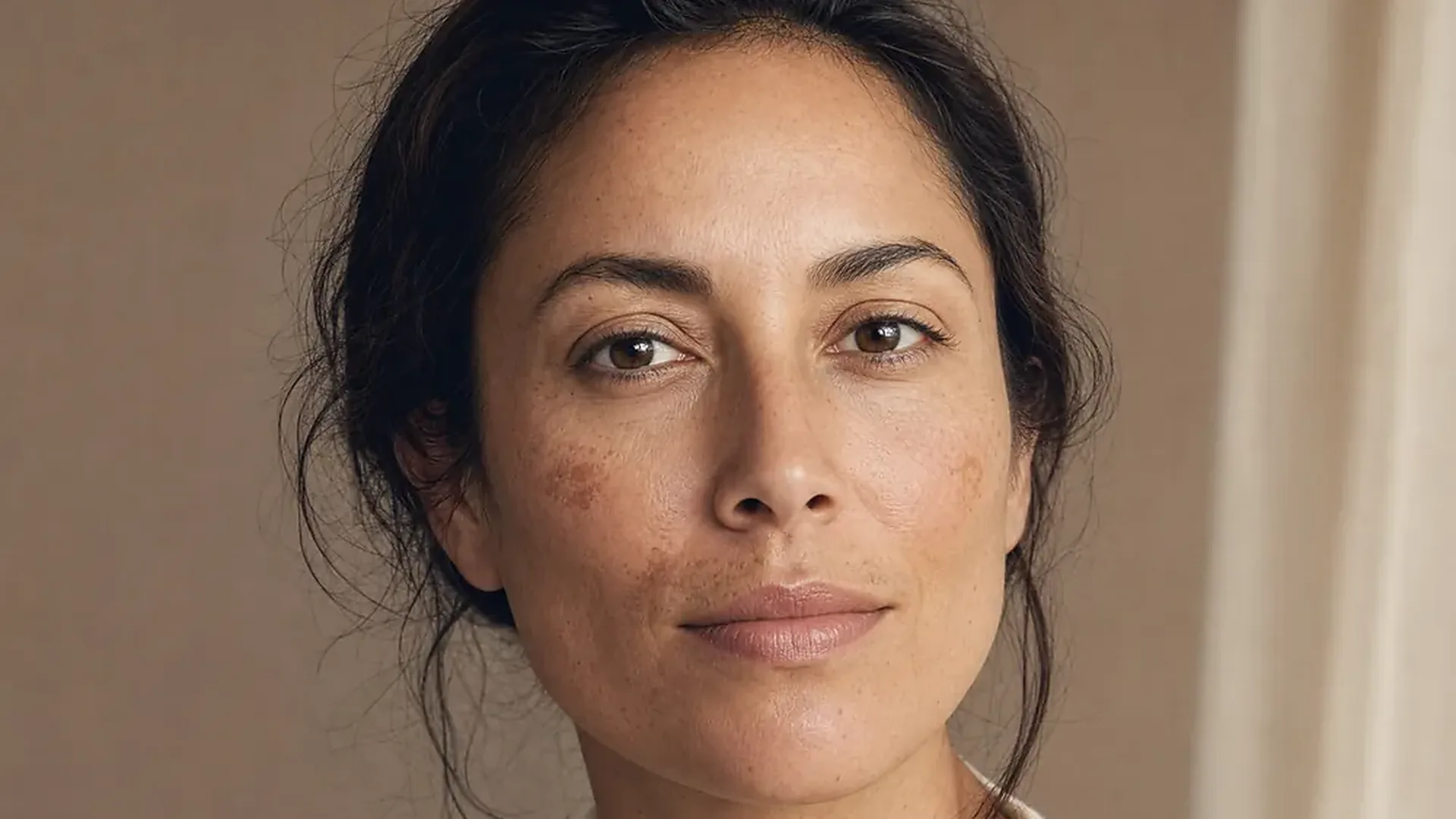 Femme au teint unifié, sans taches, regard face caméra