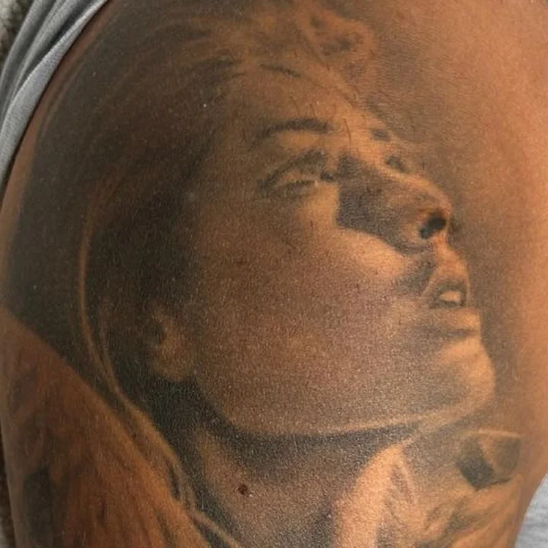 Grand tatouage réaliste représentant un visage de femme sur le bras d'un homme, avant le détatouage laser chez My Laser Tanger