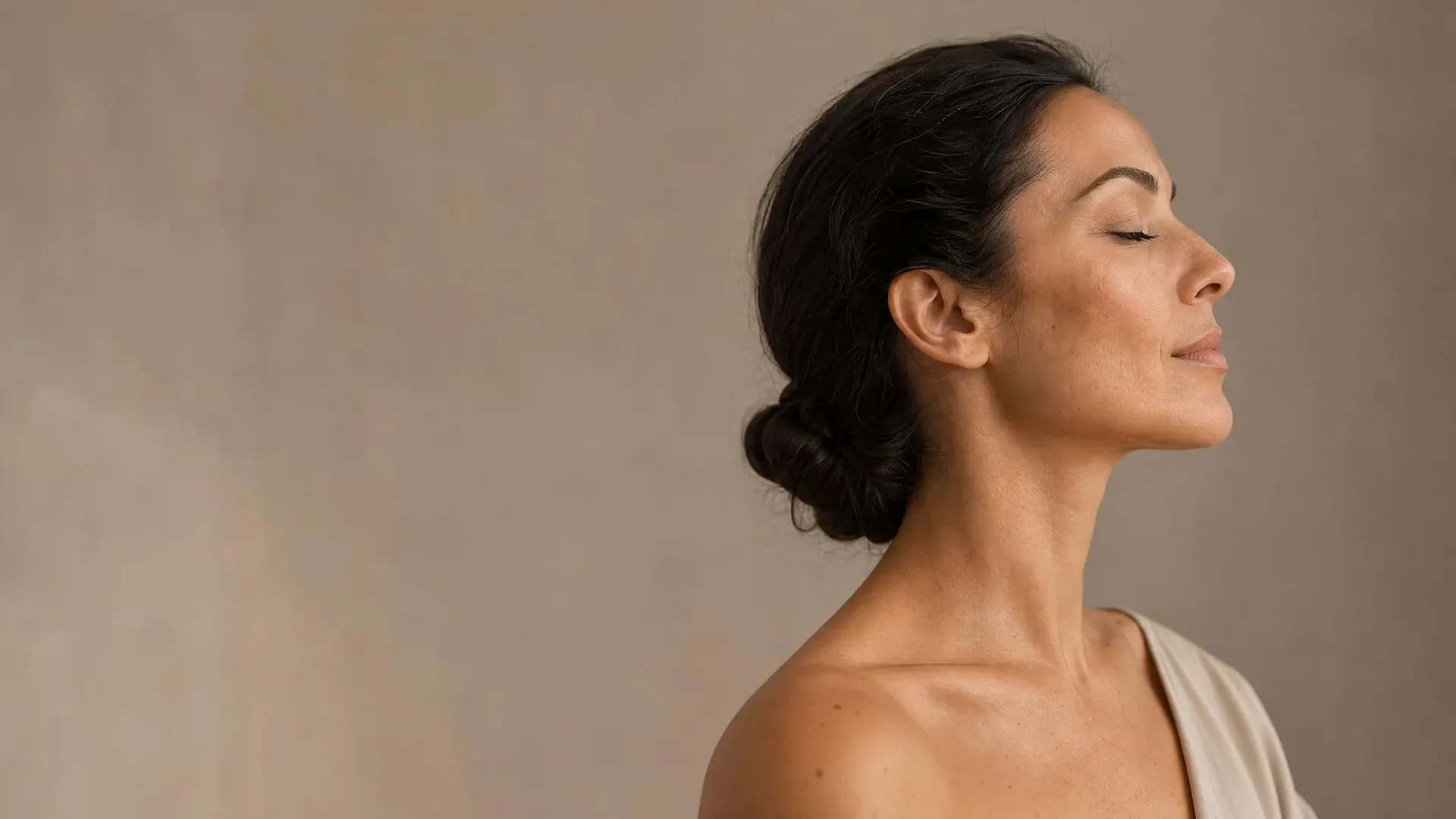 Femme de profil, yeux fermés, ovale du visage et cou dégagés sur fond beige